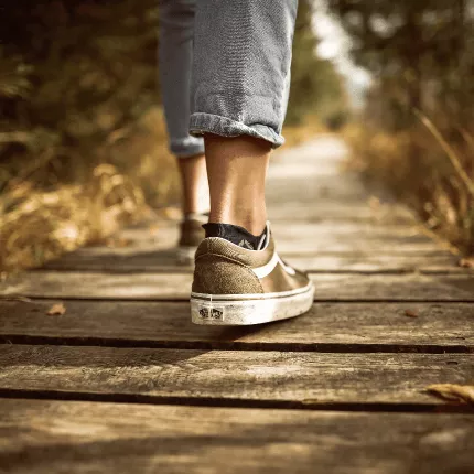 The image shows some one walking on a broad way wearing trainers and jeans